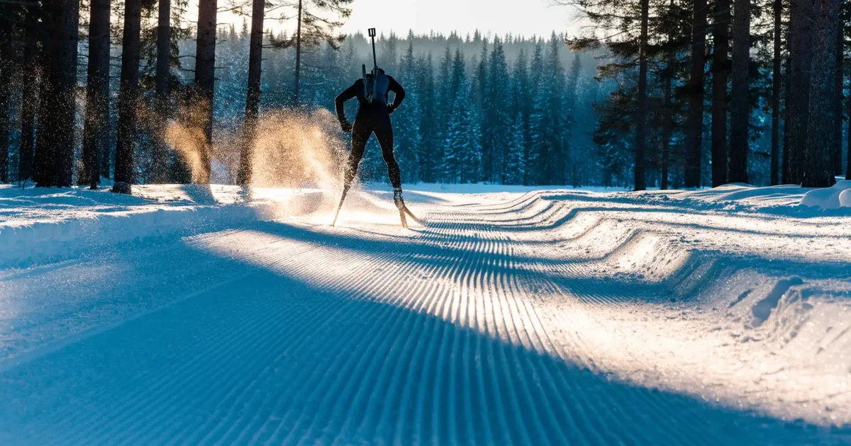 Eine verschneite Loipe zwischen Fichten im Morgenlicht, frische Spuren im Schnee, kein Mensch zu sehen.
